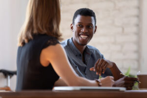Black manager listen to client preferences at business meeting, diverse teammates working together, mentor and intern talk. Job interview good first impression positive pleasant conversation concept
